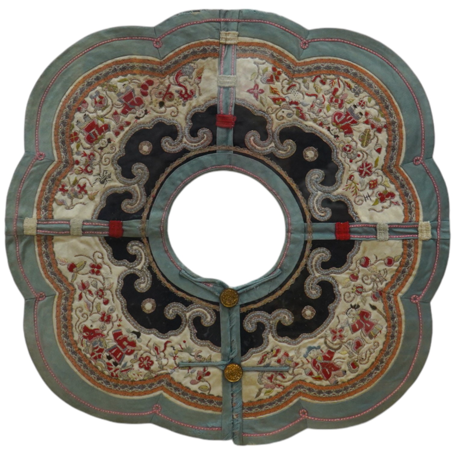 An unusual framed Chinese embroidered cloud shaped child's collar, embroidered with figures and auspicious symbols, in multi-coloured silks and gold thread, edged with braiding and a green silk border, collar 35cm wide.